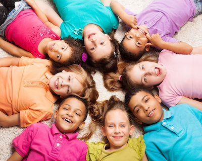 Group of diverse smiling children lying in a circle